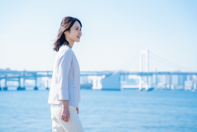 夕日を背に振り返る女性の後ろ姿。過去を振り返りながら前に進む決意を象徴している。